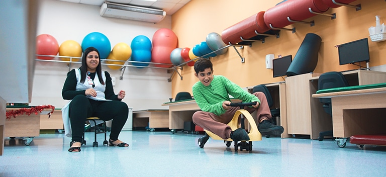 Movimento é vida Criança com deficiência física em sessão de reabilitação com terapeuta em sala equipada com bolas coloridas na AACD.
