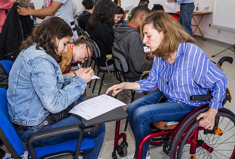 Mulher em cadeira de rodas participando de uma atividade com jovens.